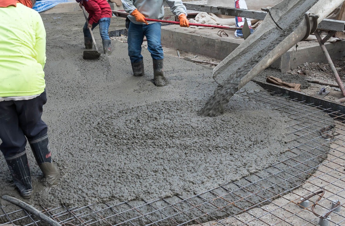 Workers pouring concrete over steel rebar mesh for a residential slab foundation in Little Rock, AR